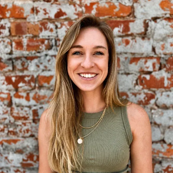 Portrait of a smiling woman in front of a brick wall