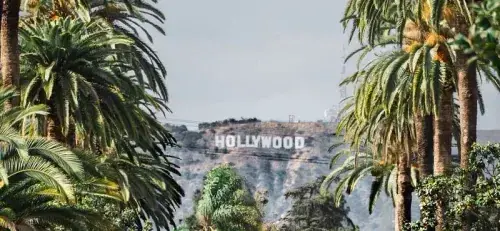 Hollywood sign on the hills of Los Angeles behind palm trees